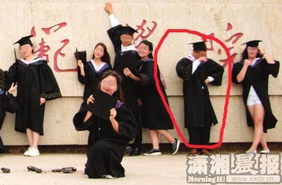 一名身穿学士服的男生正在低头抹眼睛。