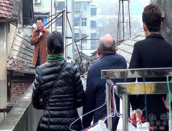 男子持刀相胁,警方、家属对其进行劝导。