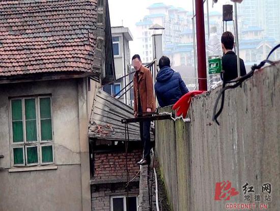 男子欲跳楼轻生,警方、家属与其进行沟通。