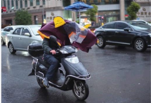 　　▲3月13日，长沙市蔡锷中路与解放西路交会处，被风掀起的雨衣挡住了电动车司机的视线。记者 唐俊 摄 