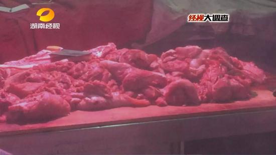 除了肉架上挂着几扇整块猪肉外，案板上堆放的全是一小块一小块的猪肉。