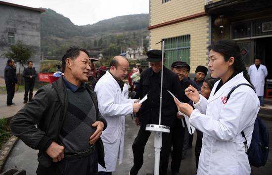     3月31日，在免费体检现场， 65岁的村民刘自强（左一）正在听昂洞卫生院院长田蕊介绍健康常识。李尕 摄