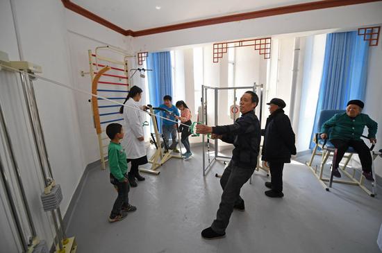 &nbsp;&nbsp;&nbsp;&nbsp;4月1日，彭秀义（右三）正在昂洞卫生院康复中心使用康复健身器材。李尕 摄