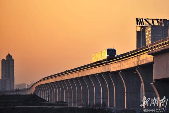 2017年2月27日，夕阳映照下的磁浮列车通过长沙磁浮快线浏阳河大桥段。湖南日报记者 童迪 摄