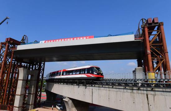 2017年5月4日，长沙市机场大道与磁浮快线交汇处，一列磁浮列车从施工中的钢箱梁下穿过。湖南日报记者 田超 摄