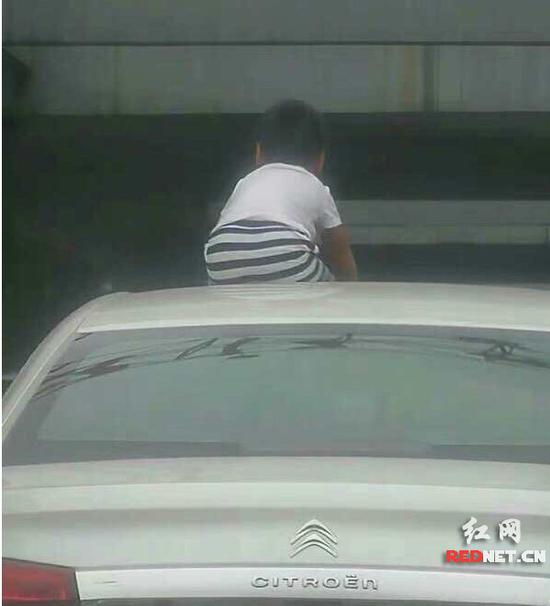  在湘江世纪城某路口，路人惊讶地看到一辆白色轿车车顶上，坐着一个五六岁的小男孩。