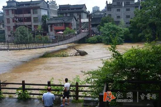 (乾州古城景区,万溶江水位暴涨,工作人员在关闭的吊桥前值守)