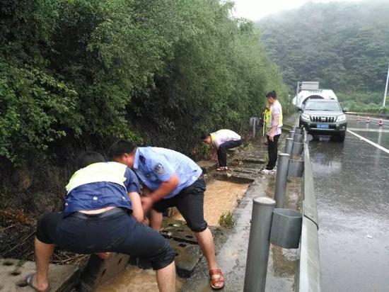 雨势很大，民警只能徒手打开排水通道加快路面排水