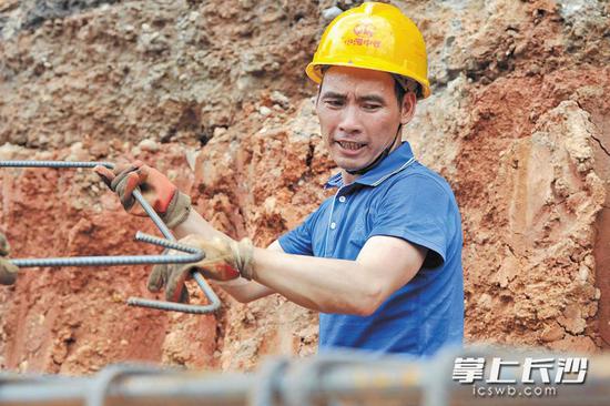 烈日下,钢筋工李小兵额头上沁出了大颗的汗珠。