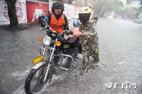 　7月30日，在福建省晋江市深沪镇，民警帮助群众推行一辆涉水熄火的摩托车。