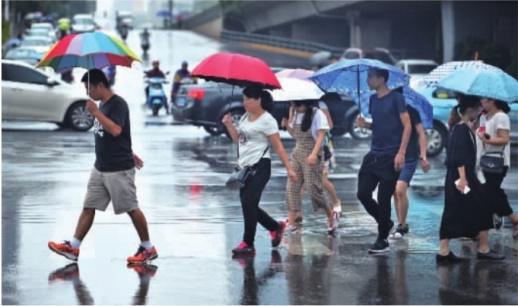　　8月1日，长沙城区街头，市民撑伞在雨中出行。受到双台风外围云系的影响，我省上空也生成了对流云团，气温一降再降，为星城带来久违的清凉。   记者 李健  摄