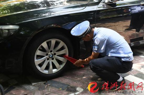 珠江南路人行道上，一辆违规占用人行道的机动车被城管队员予以锁车处罚。