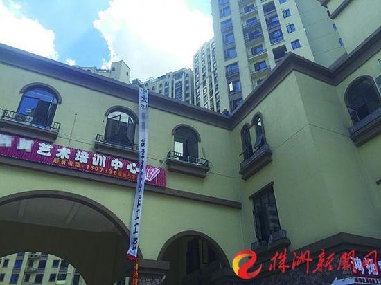 三一歌雅郡,两名农民工坐在楼顶边,外墙挂着维权横幅(记者贺天鸿摄)