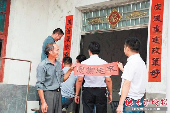 杨东木(左一)在新房贴上大家送来的对联。长沙晚报通讯员 刘静 摄