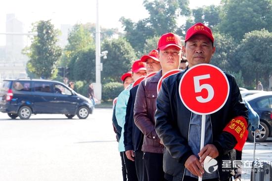 （当绿灯亮起时，志愿者们侧身站立，收回提示牌，排出四列出入口方便行人有序通过斑马线。）