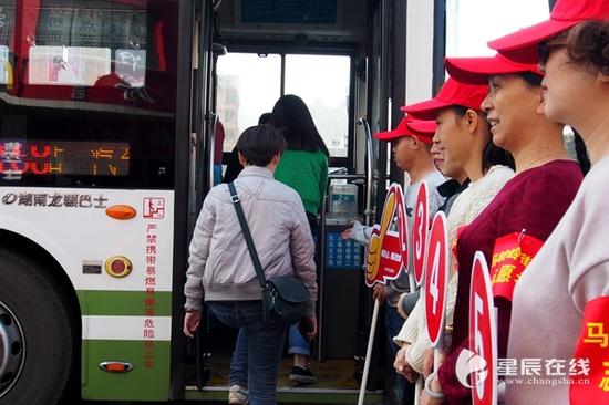 （在汽车东站公交站排队礼让示范点，志愿者引导市民上下公交车。）