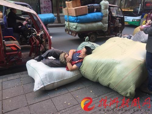 ▲ 搬运工累了,睡在货物上。(吴楚、廖明 摄)