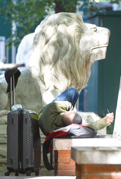 10月21日，长沙天气晴朗，出行的市民躺在五一大道的石凳上休息，一旁的“石狮子”仿佛是他的护卫。　图/记者吴琳红