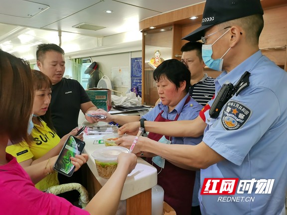 孙宏伟（右一）协助餐车工作人员为乘客分发餐食。