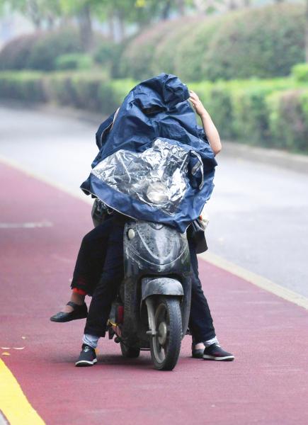 10月22日,长沙贺龙体育中心附近,市民穿上雨衣,以方便在雨中骑行。图/记者金林