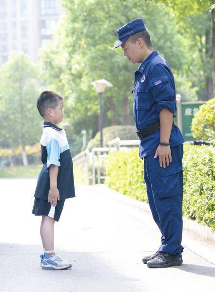 △ 8 月 31 日,长沙市实验小学梅溪湖学校,一年级新生正在向消防队员学习站姿。图 / 记者谢长贵