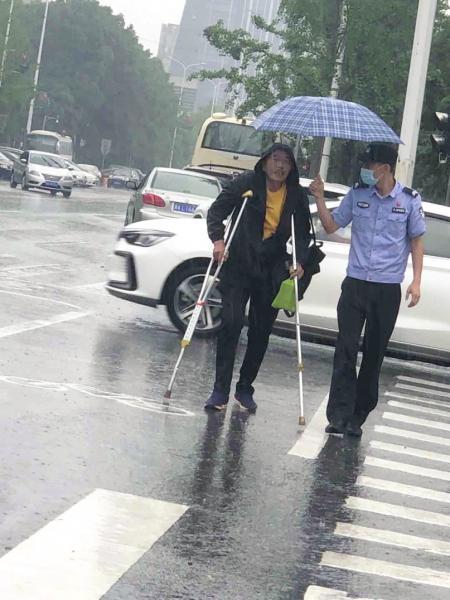 5 月 30 日，长沙府中路与观沙路交会处，辅警赵喻佳为拄拐杖过马路的老人撑伞。 图 / 受访者提供