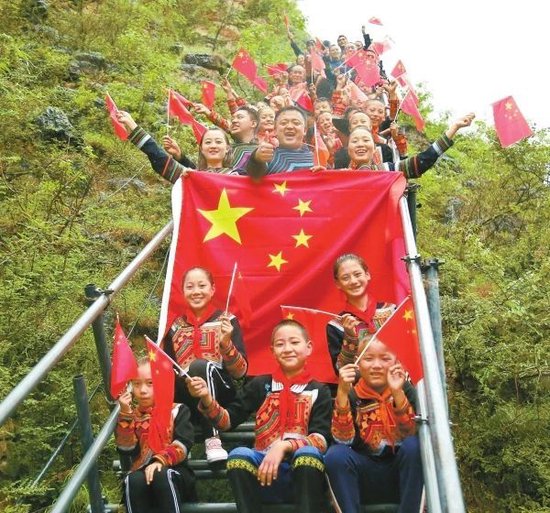 悬崖村钢梯完工后,悬崖村学生在钢梯上合影。(资料图片)阿克鸠射 摄