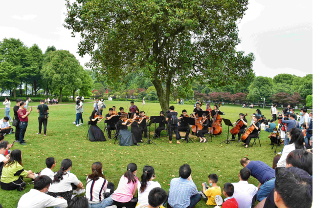 ▲5月1日,夏之恋·橘子洲假日音乐会上演,游客坐在草坪上听交响乐。