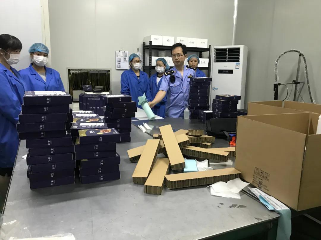 市场监管执法人员在生产线末端的包装车间检查固定证据