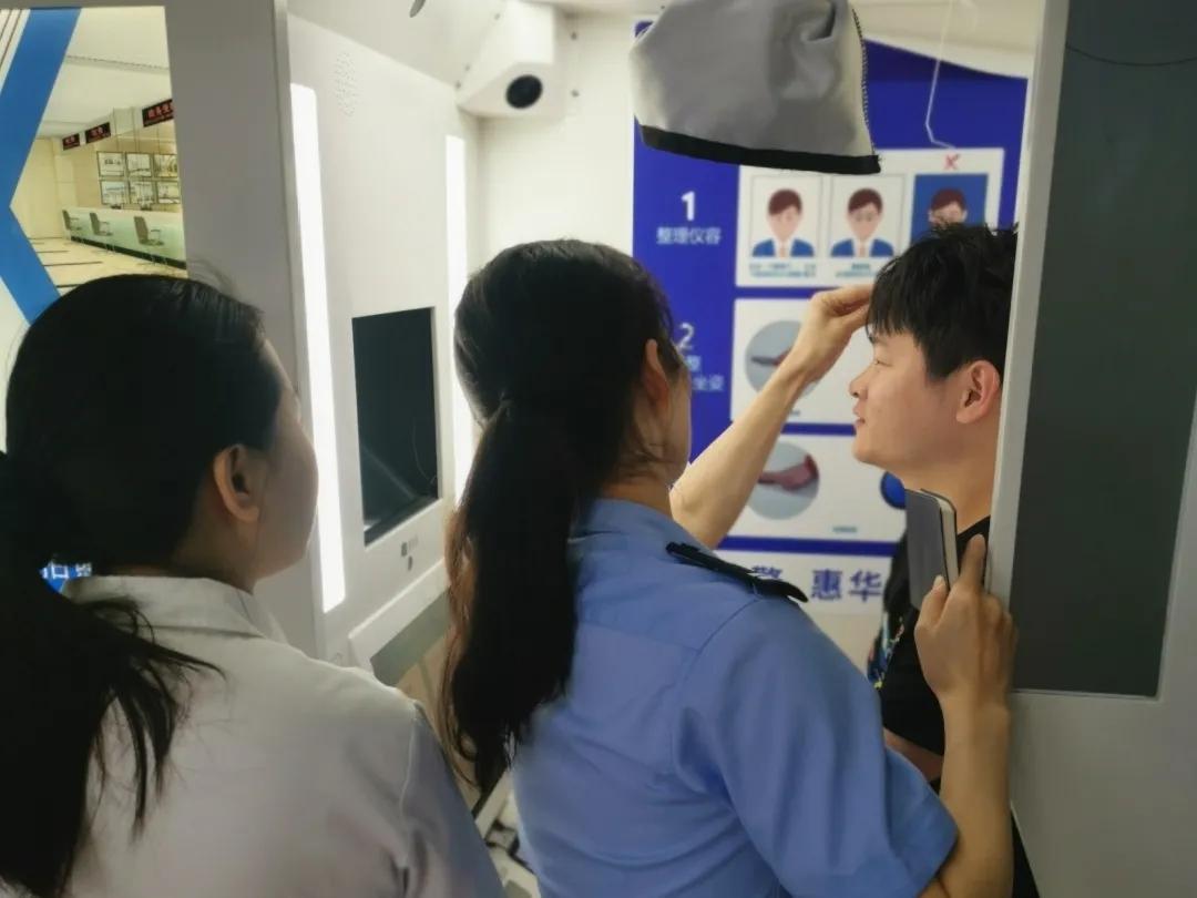 一名群众在工作人员的指导下,体验身份证自助办理功能
