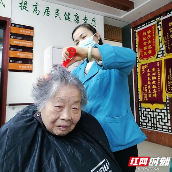 3月17 日,康乃馨韶山路社区居家养老服务中心内,护理员姚运娥为老人修剪头发。