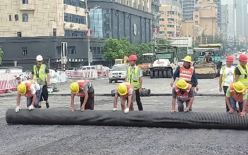 8月16日，在全封闭的长沙橘子洲大桥上，工人们正在进行土工格栅摊铺。 记者 陈月红 摄