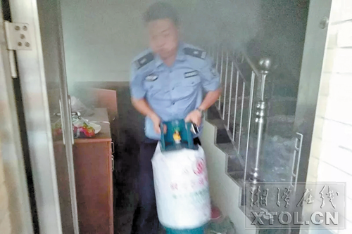 民警刘晓军冒着浓烟抱出液化气罐。（湘乡公安供图）