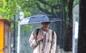 3月23日,长沙河西桃子湖路,突降大雨,年轻人撑伞前行。图/周翼