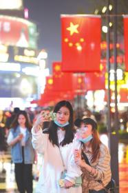 10月1日晚,长沙黄兴路,女孩以国旗为 背景自拍。 图/记者吴琳红