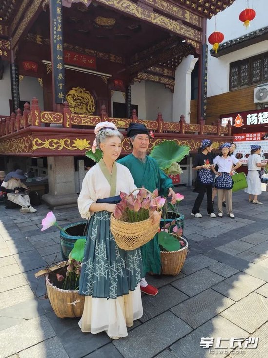 快闪活动中,两位老人给市民游客送荷花。