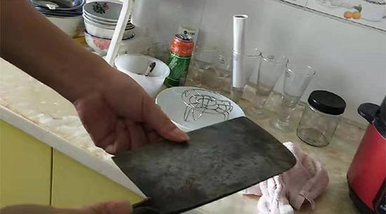 屈中亚展示妻子写保证书前拿来砍人的刀。    澎湃新闻记者 谭君 图