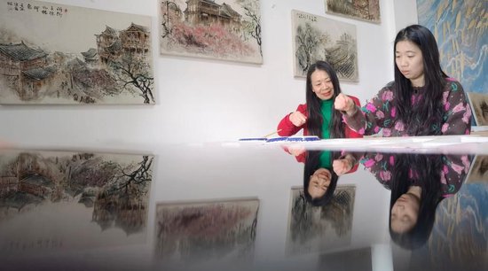 　　2025年3月16日，在穿紫河畔的常德河街，麻质画艺人李健鹰（左）在指导学员作画。 新华社记者 赵仲志 摄