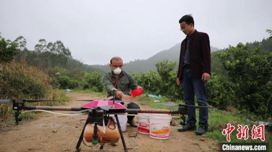 农机手正往无人植保机灌农药。新田县供图