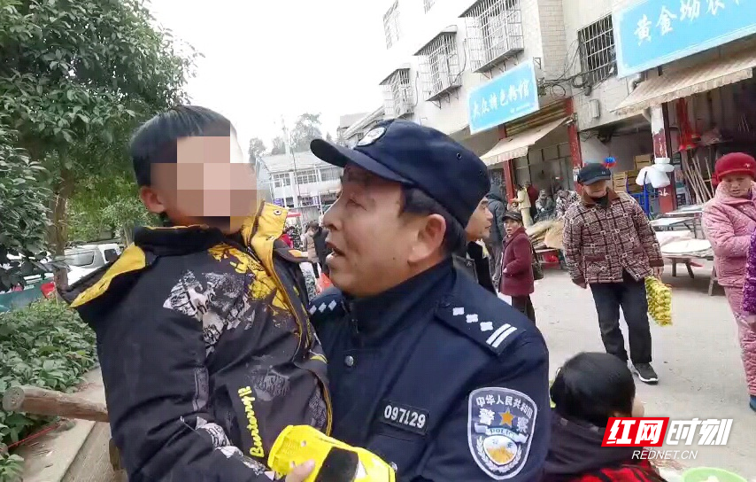 民警将小男孩抱起,询问一些基本情况。