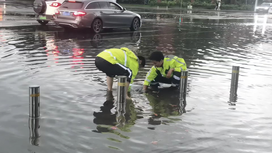 潇湘大道景园路口,长沙岳麓大队七中队交警徒手清理下水道的垃圾,加快积水排放。