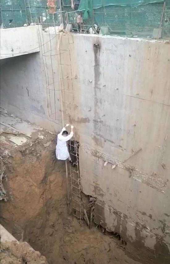 8 月 25 日,隆回县桃洪中路一处建筑工地,医生宋东阳顺着简易梯子爬下去,准备救治伤员。图 / 受访者提供