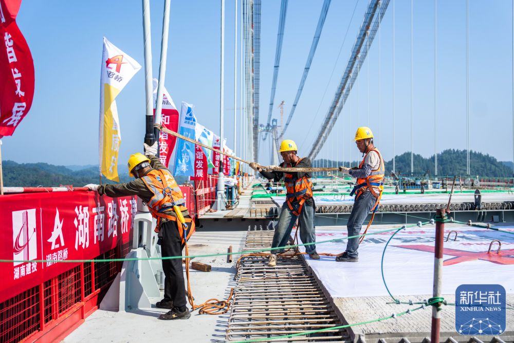 ↑ 8月3日,在张官高速洞庭溪沅水特大桥施工现场,工人在固定刚被提升的钢混结合梁。