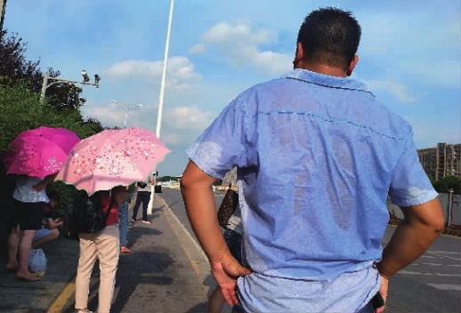 7月4日，长沙市湘府西路上，市民在烈日下等公交车，身上汗流浃背。当天，省气象台发布高温黄色预警，晴热高温天气持续，最高气温达36℃。记者 郭立亮 摄