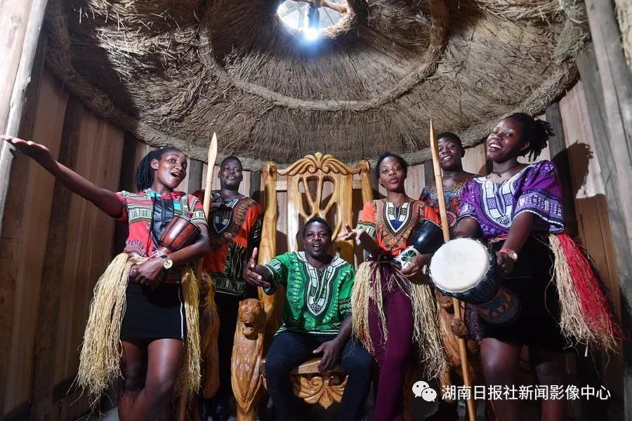 6月15日，河村非洲文化园，Tom（汤姆）坐在他参与制作的酋长椅上和伙伴们一起向湖南人民发出邀请“非洲欢迎你”。 