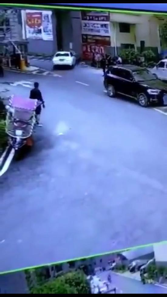 △视频远处可见白色奥迪轿车将摩托车撞到墙壁上。视频截图