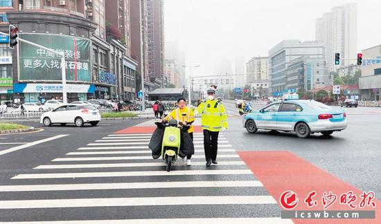 交警对一名未戴安全头盔的电动车骑行者进行劝诫。 龙雨泉供图