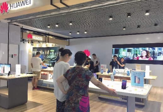 5月18日晚,数名消费者在苏宁五一广场云店华为柜台选购商品。 记者 黄亚苹 摄