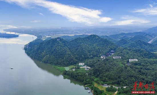 (蓝天白云下的昭山风景区与远处层次分明的山峦构成一幅绿意盎然的山水画卷。辜鹏博 摄)