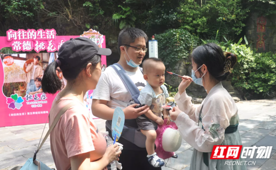常德桃花源景区员工配上香囊,为游客点朱砂、抹雄黄,寻回节日的仪式感。
